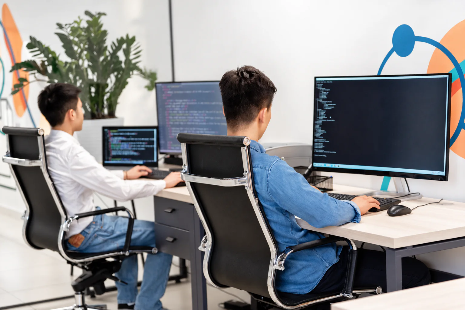 Two professionals working with code on their computers.