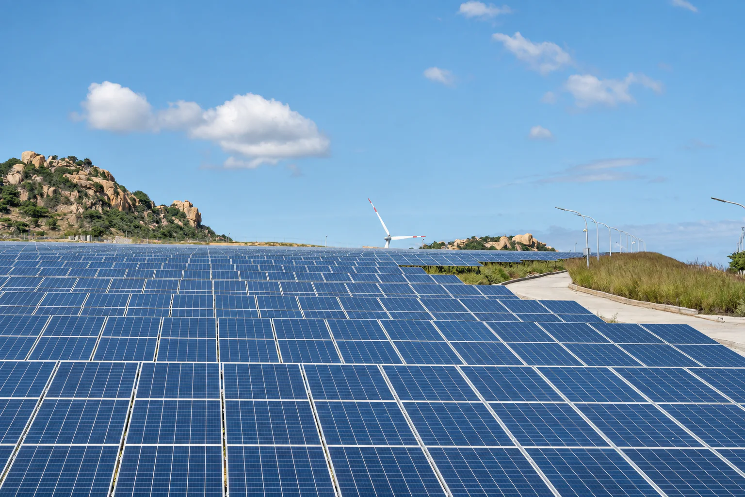 Solar panels in the foreground with hills in the background.