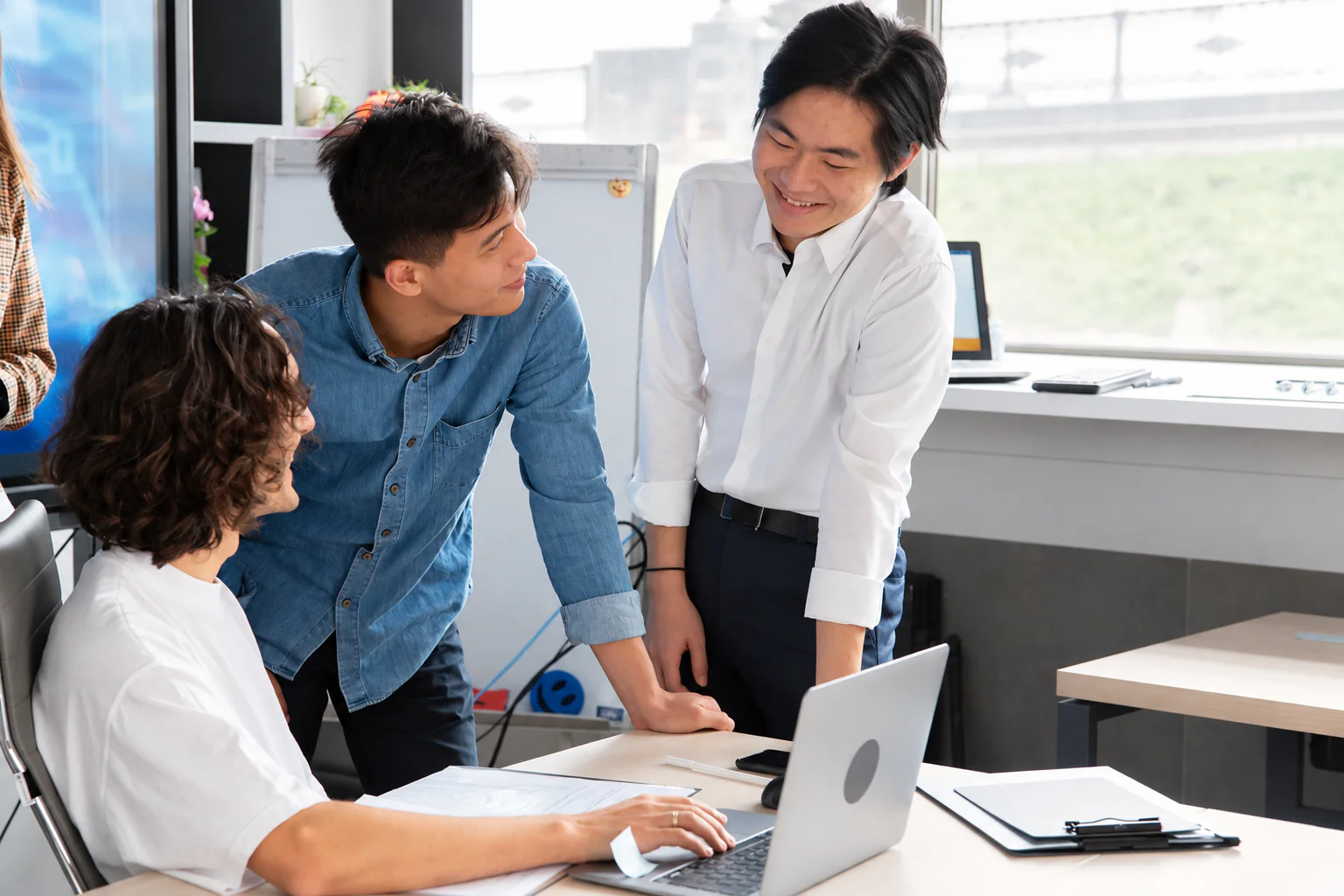 Professionals collaborating around a laptop.